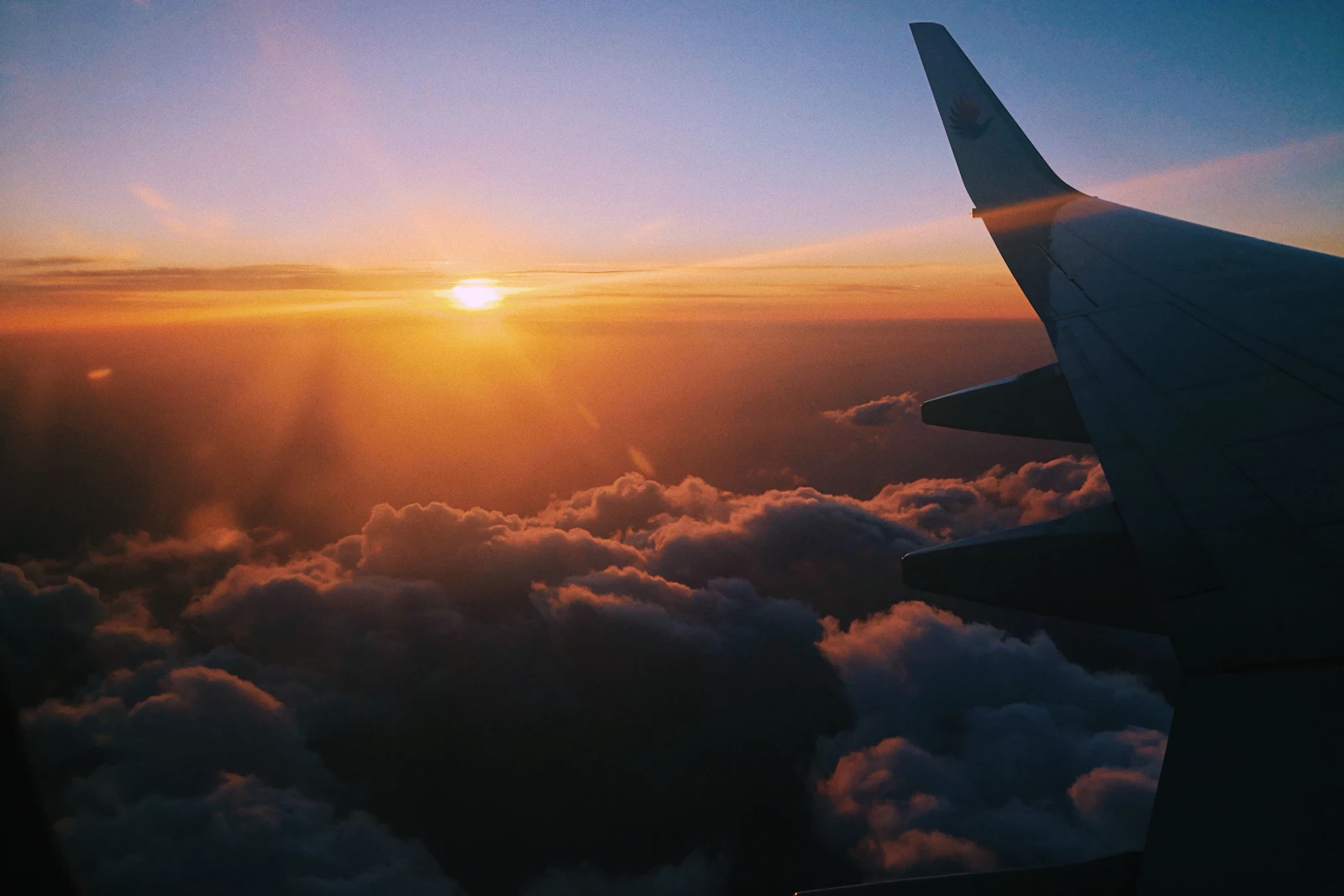 Asa de avião sobre as nuvens ao entardecer
