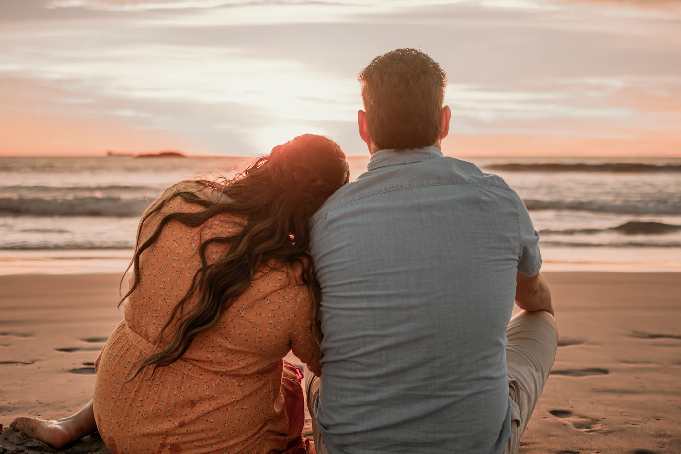Casal sentado na praia a ver o pôr do sol
